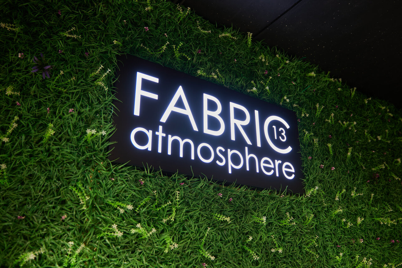 Наша световая вывеска FABRIC13 atmosphere на зелёной стене в зале